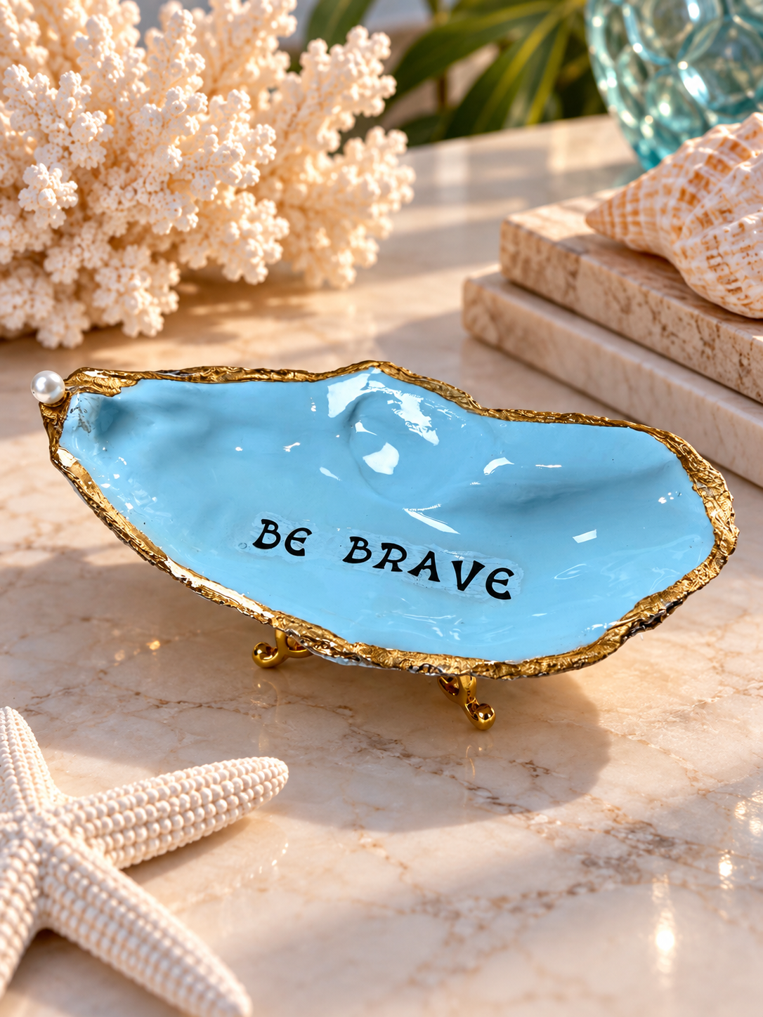 Sky-blue decorative oyster shell with Be Brave lettering and gold-toned edges