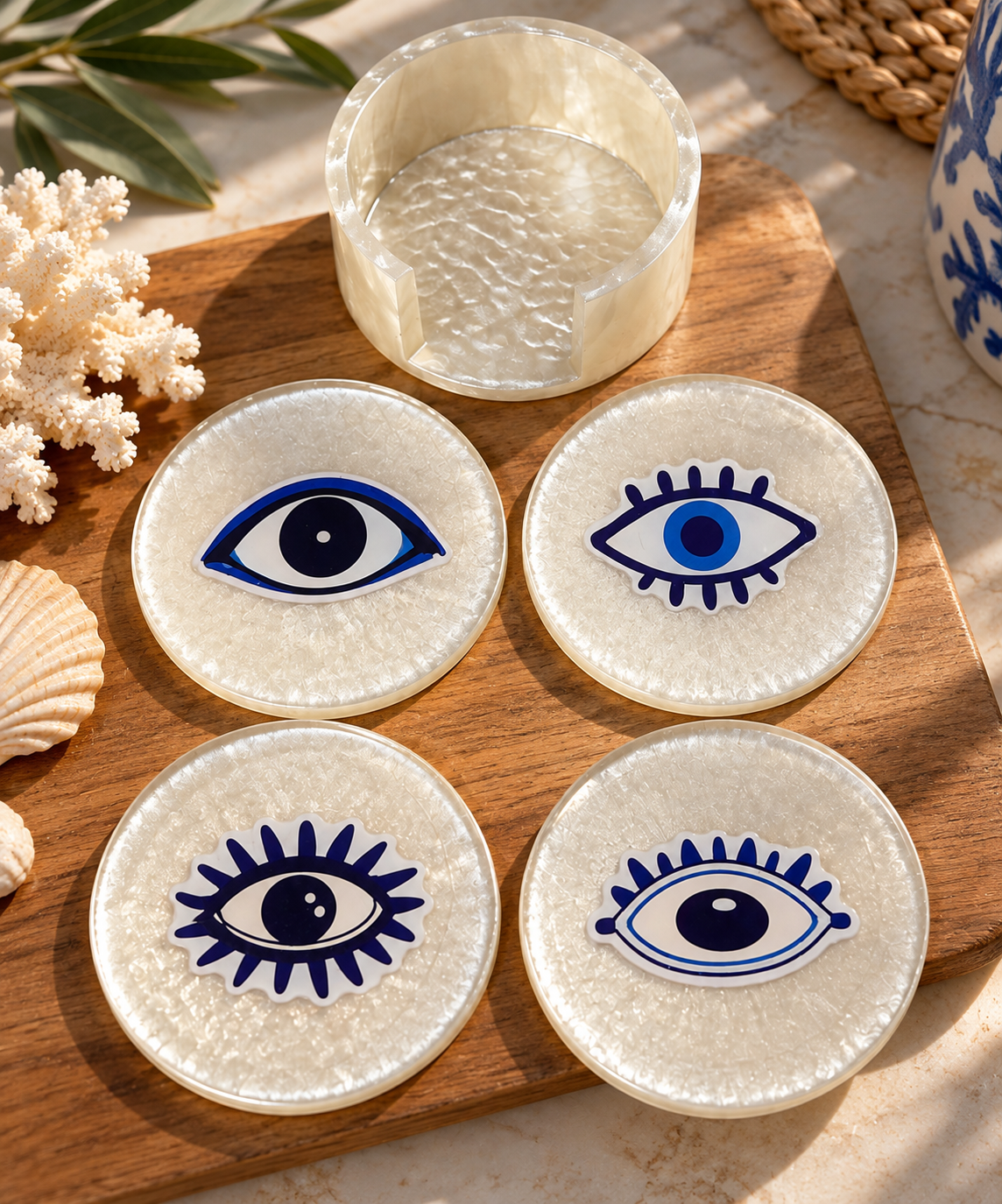 Four pearlescent coasters with blue evil eye designs and a matching holder
