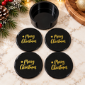 Four black Christmas coasters with gold-colored Merry Christmas lettering and matching black holder
