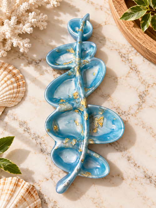 Blue and white leaf-inspired jewelry dish with gold-colored accents and curved compartments